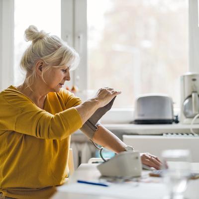 Woman taking her blood pressure in a kitchen